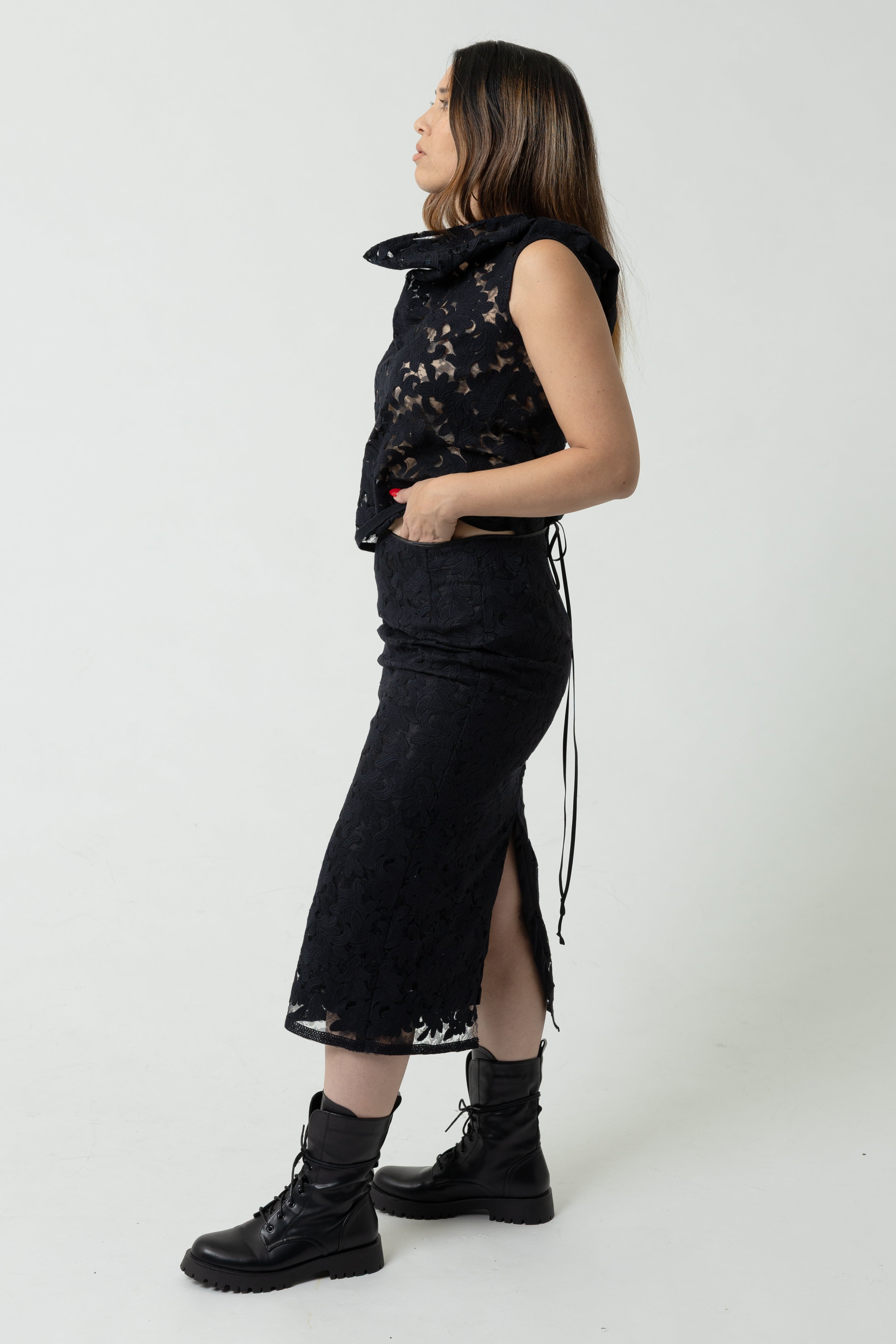 Woman wearing a black sleeveless top and skirt with a hood on a white background