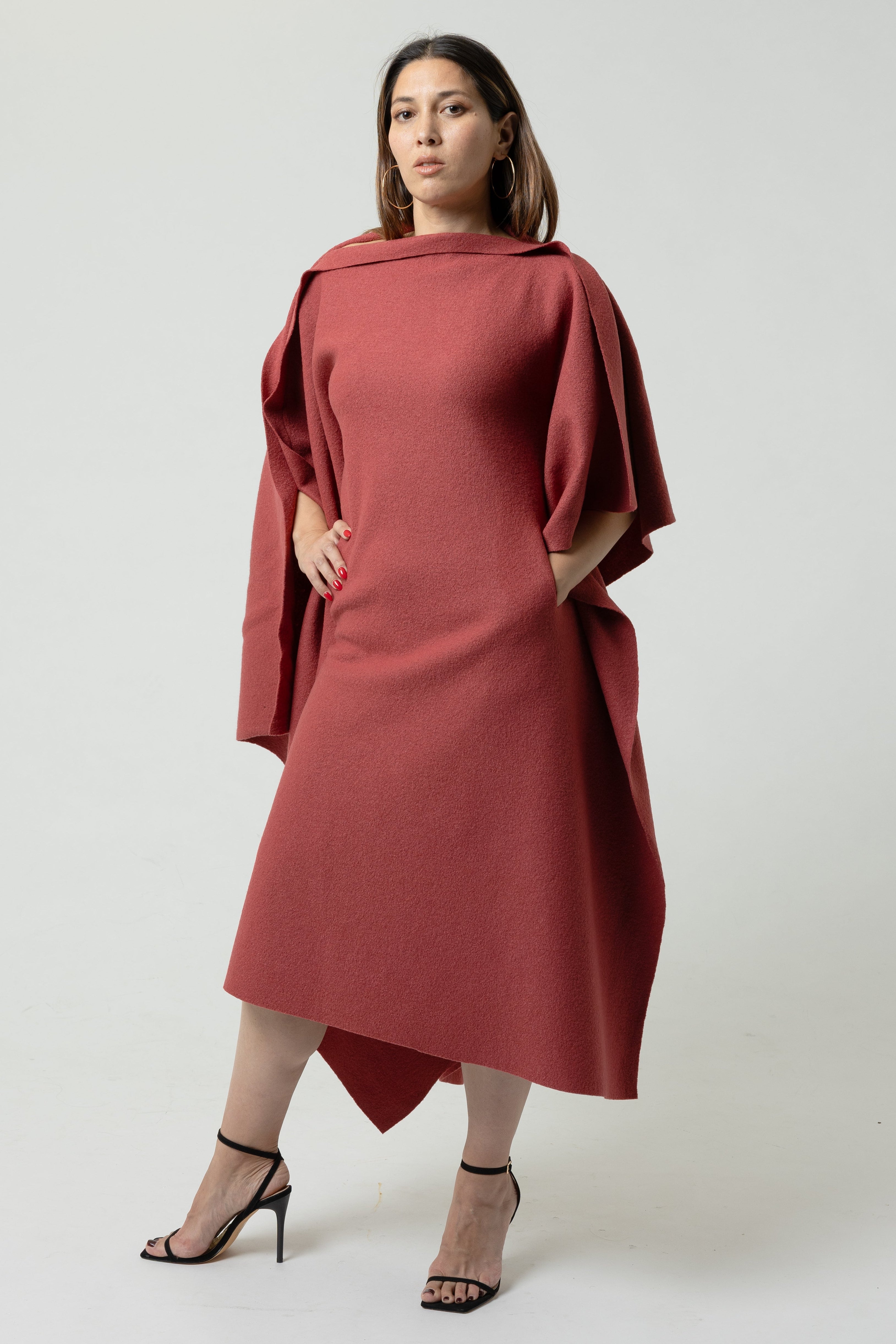 Woman wearing a red dress with a cape on a white background