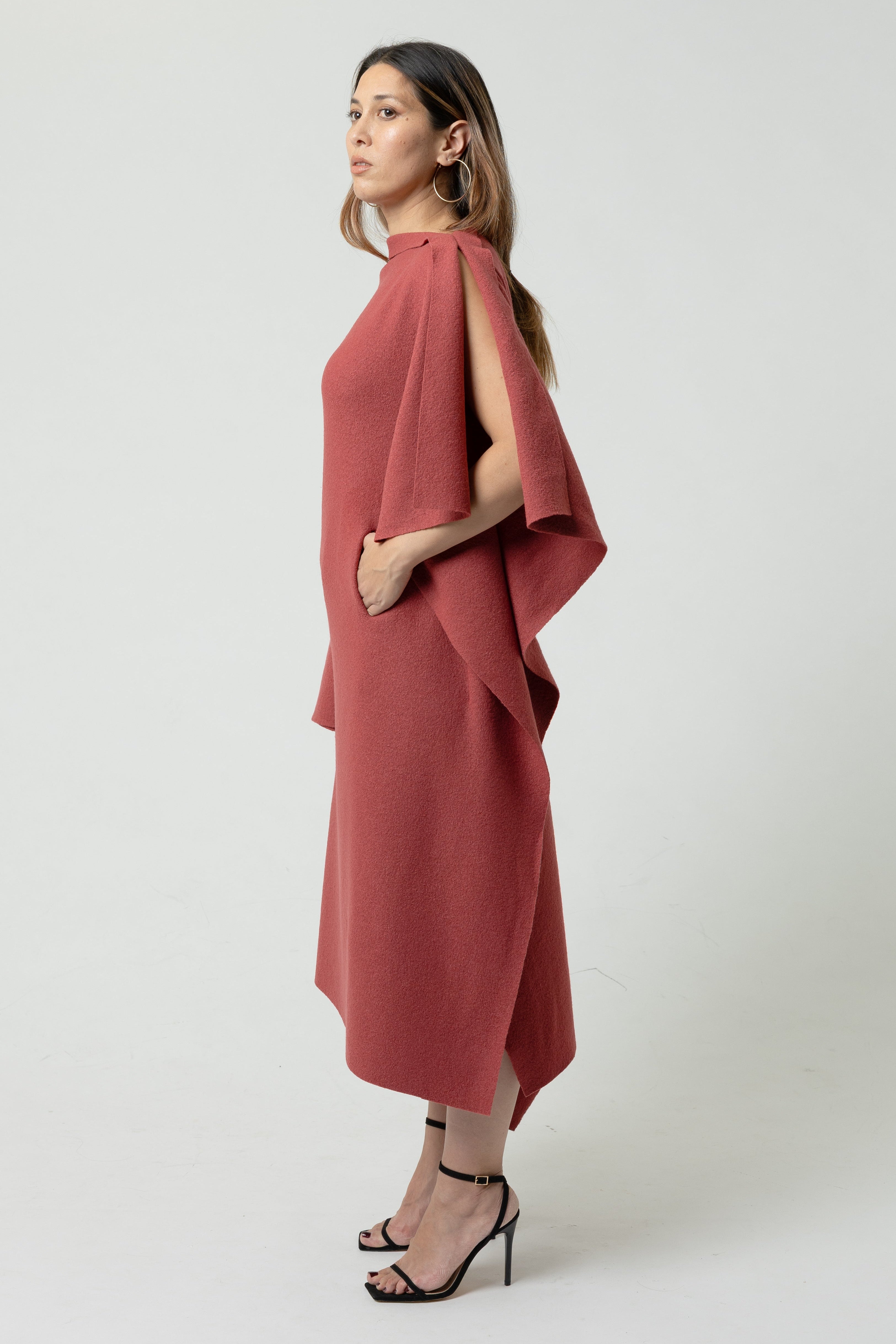 Woman wearing a red dress with a cape effect on a white background