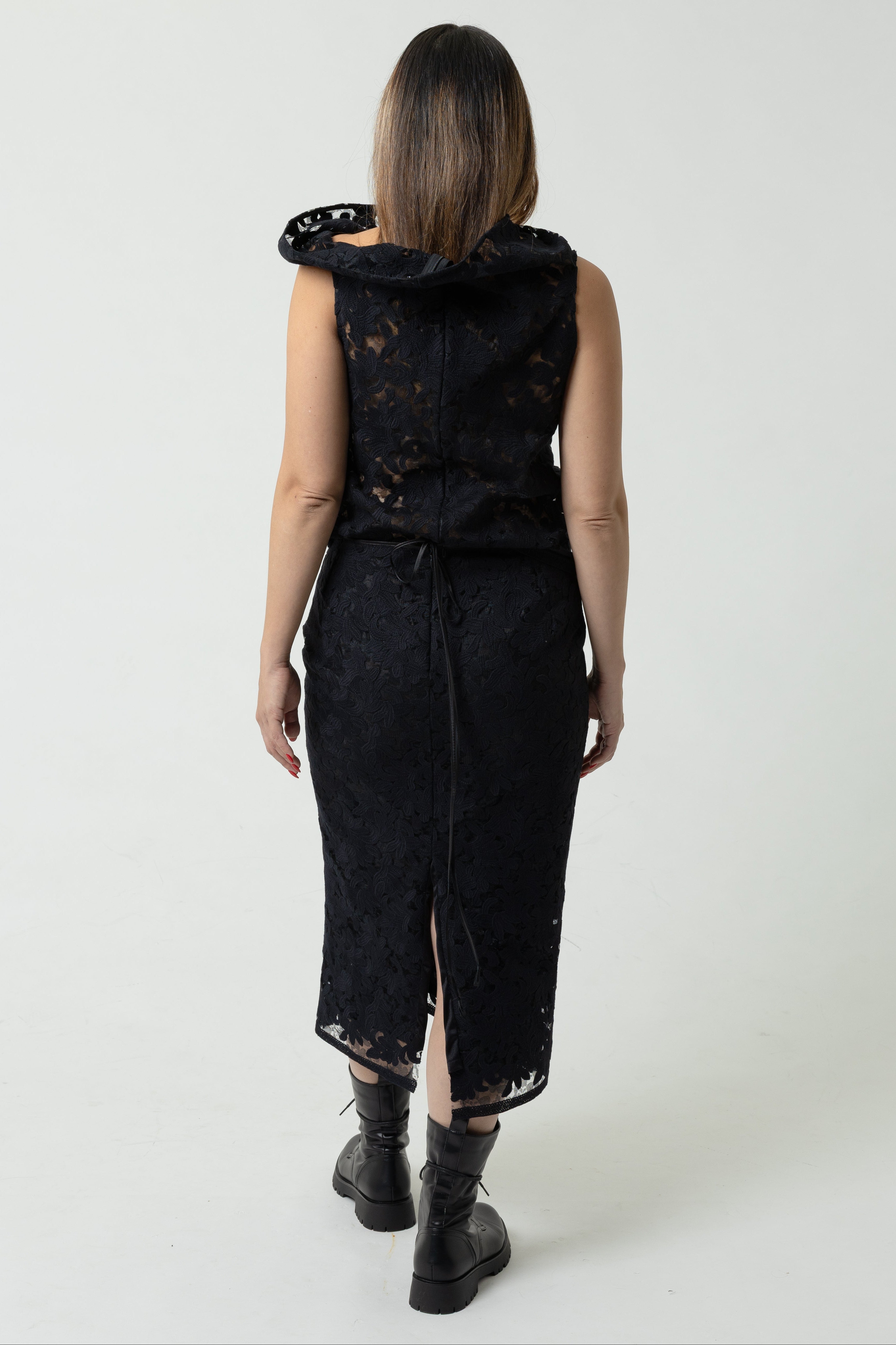 Person wearing a black sleeveless dress with a hood on a white background