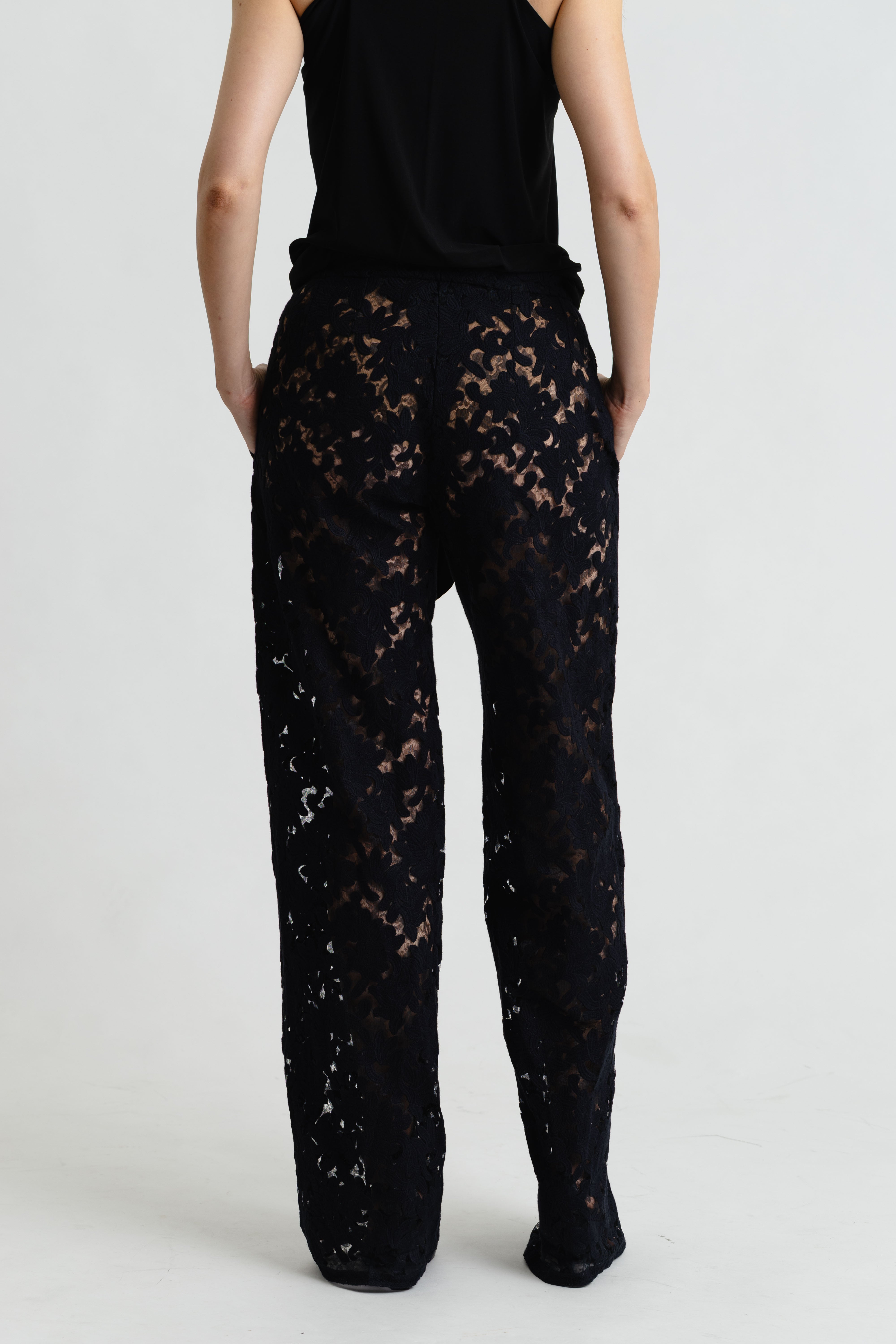 Person wearing black lace pants on a plain background