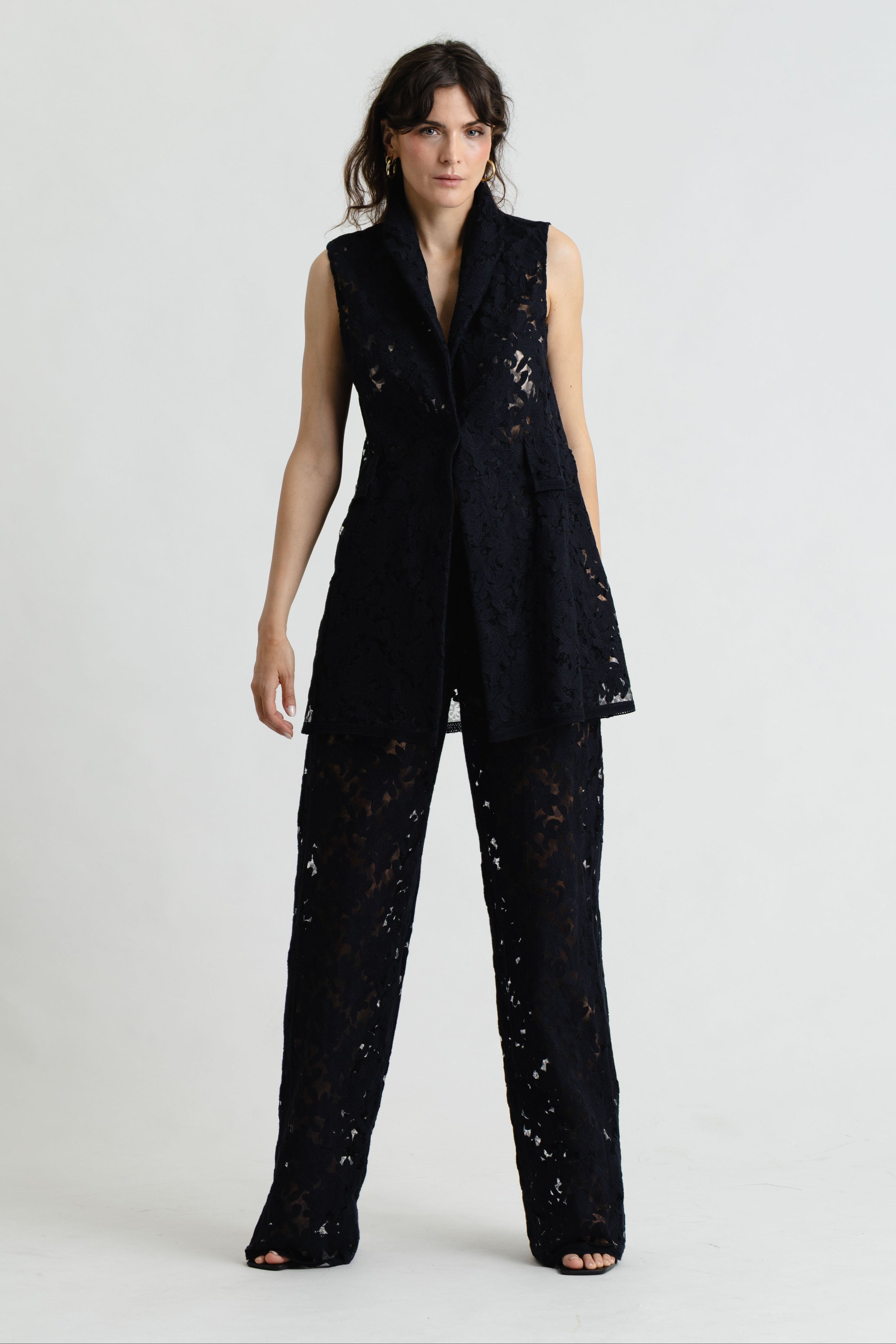 Woman wearing a black lace jumpsuit on a white background