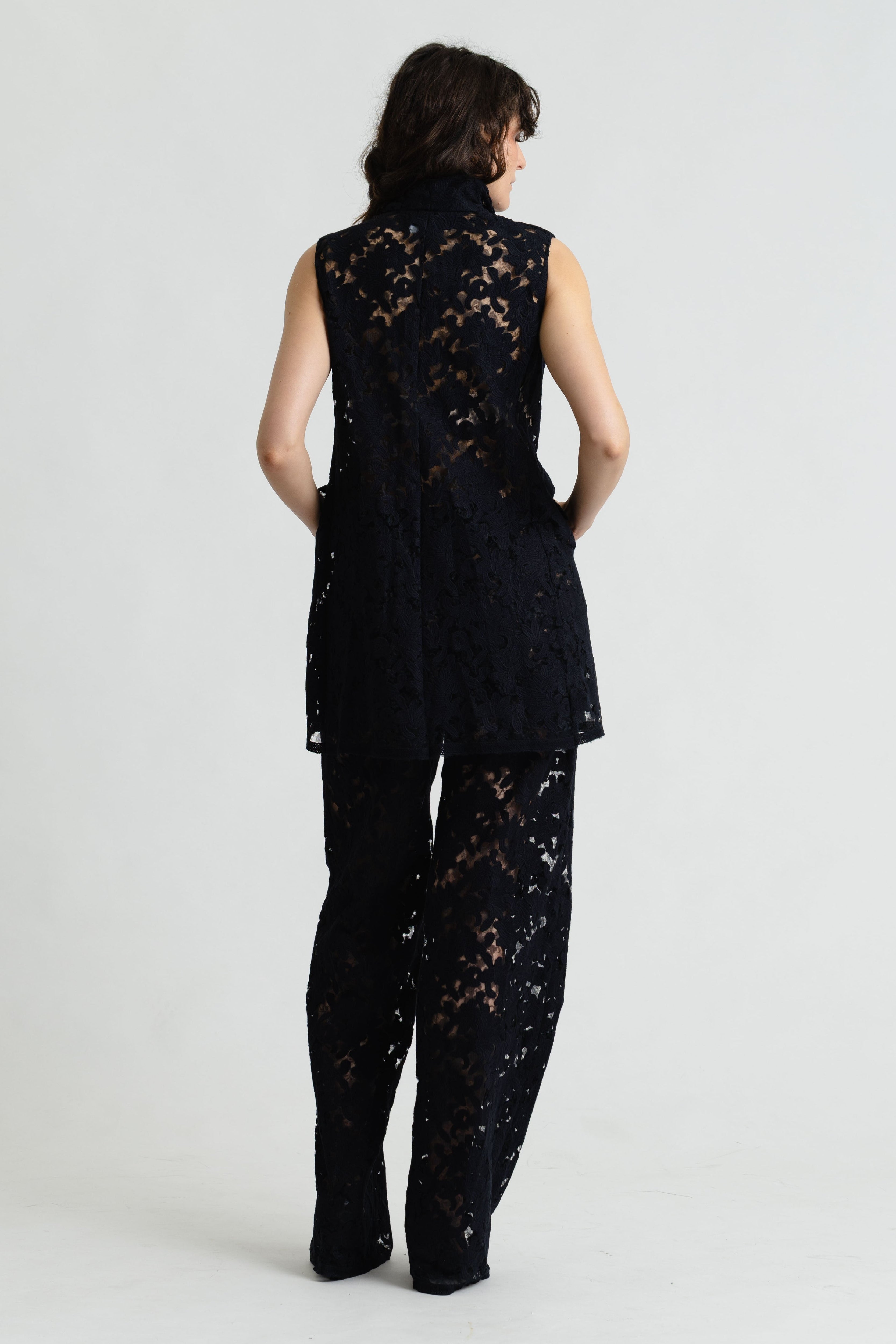 Person wearing a black lace outfit on a white background