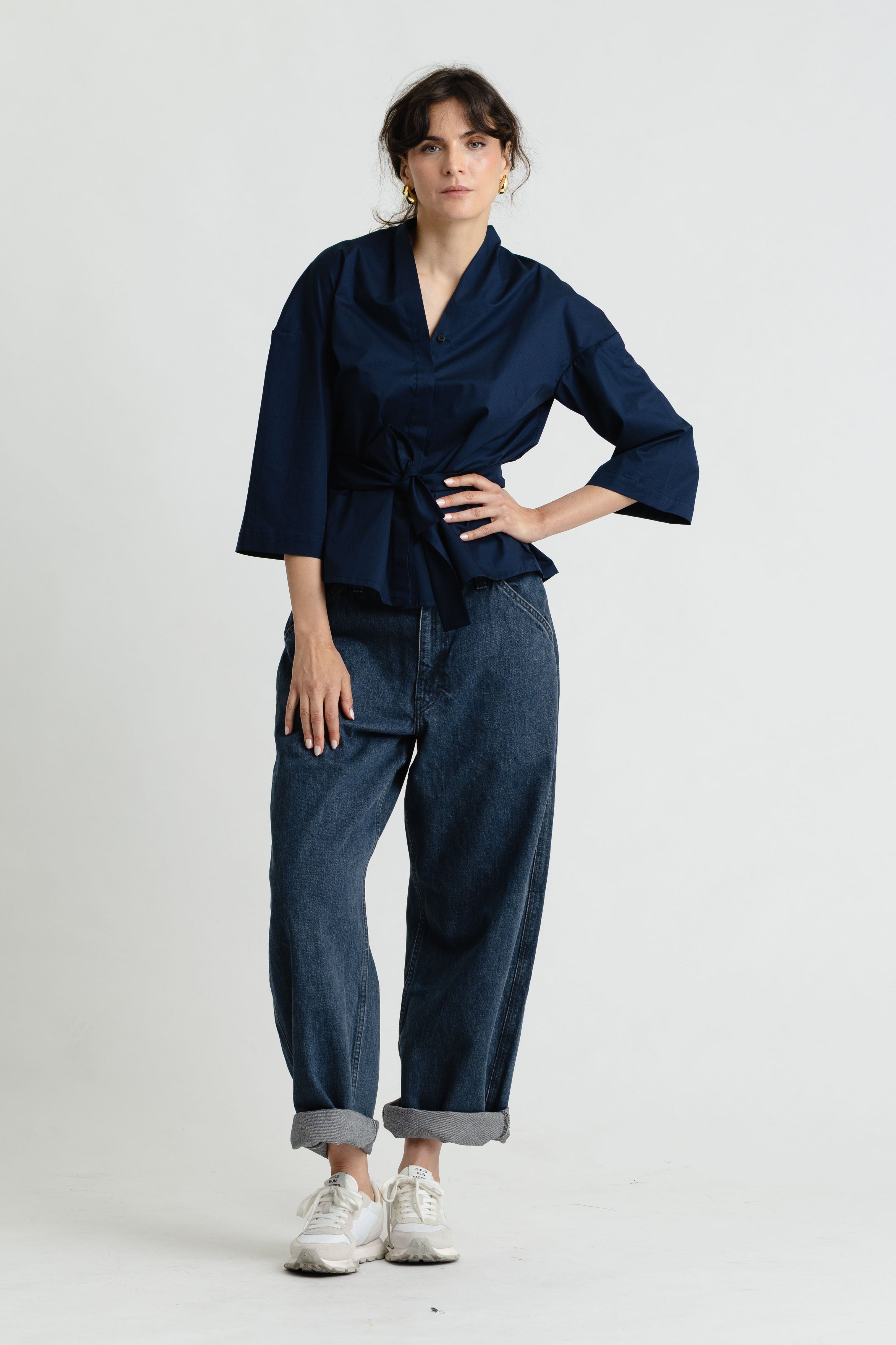 Person wearing a navy blue top and jeans on a white background