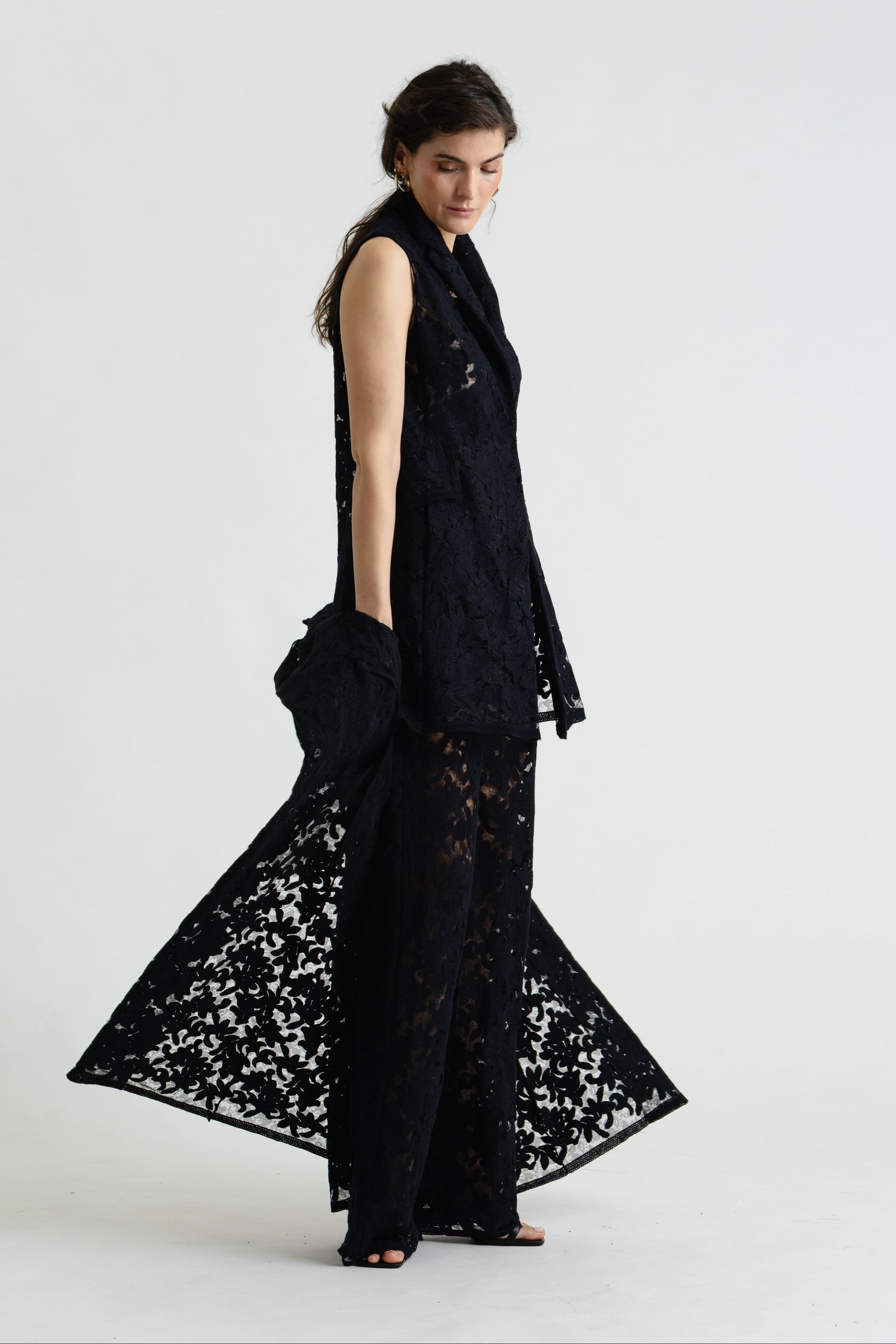 Woman wearing a black lace dress against a white background