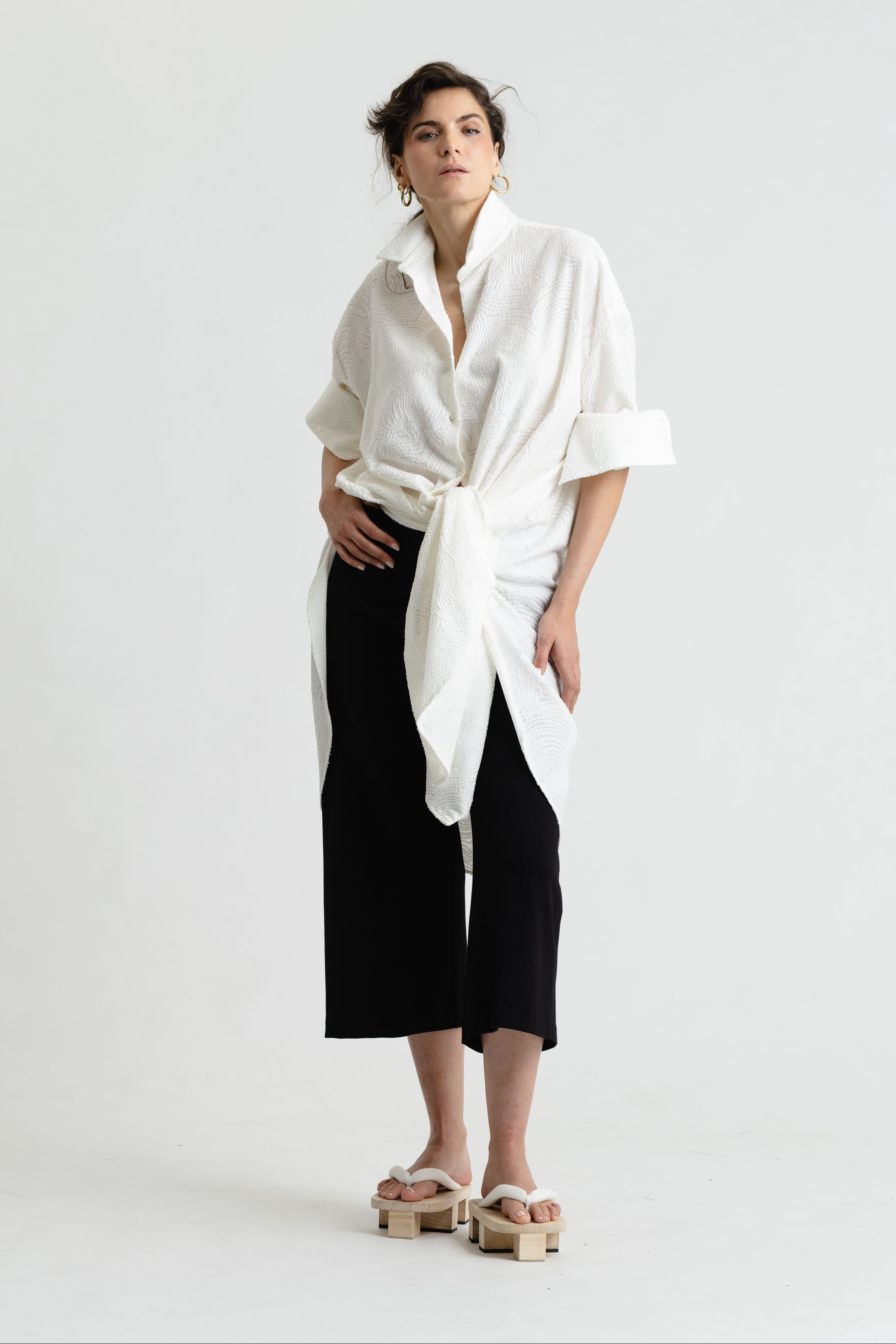 Person wearing a white shirt and black pants on a white background