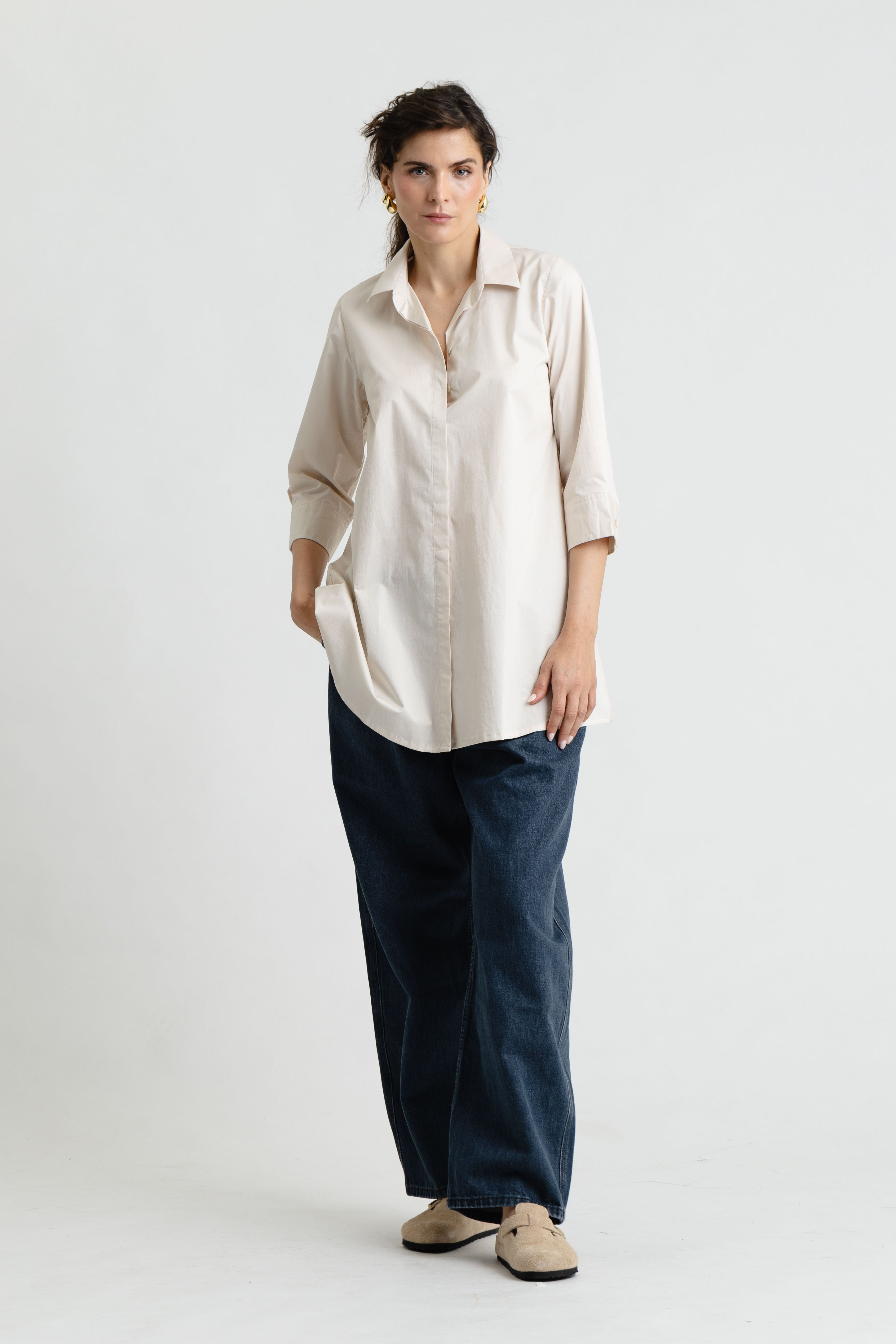 Woman wearing a beige shirt and blue pants on a white background