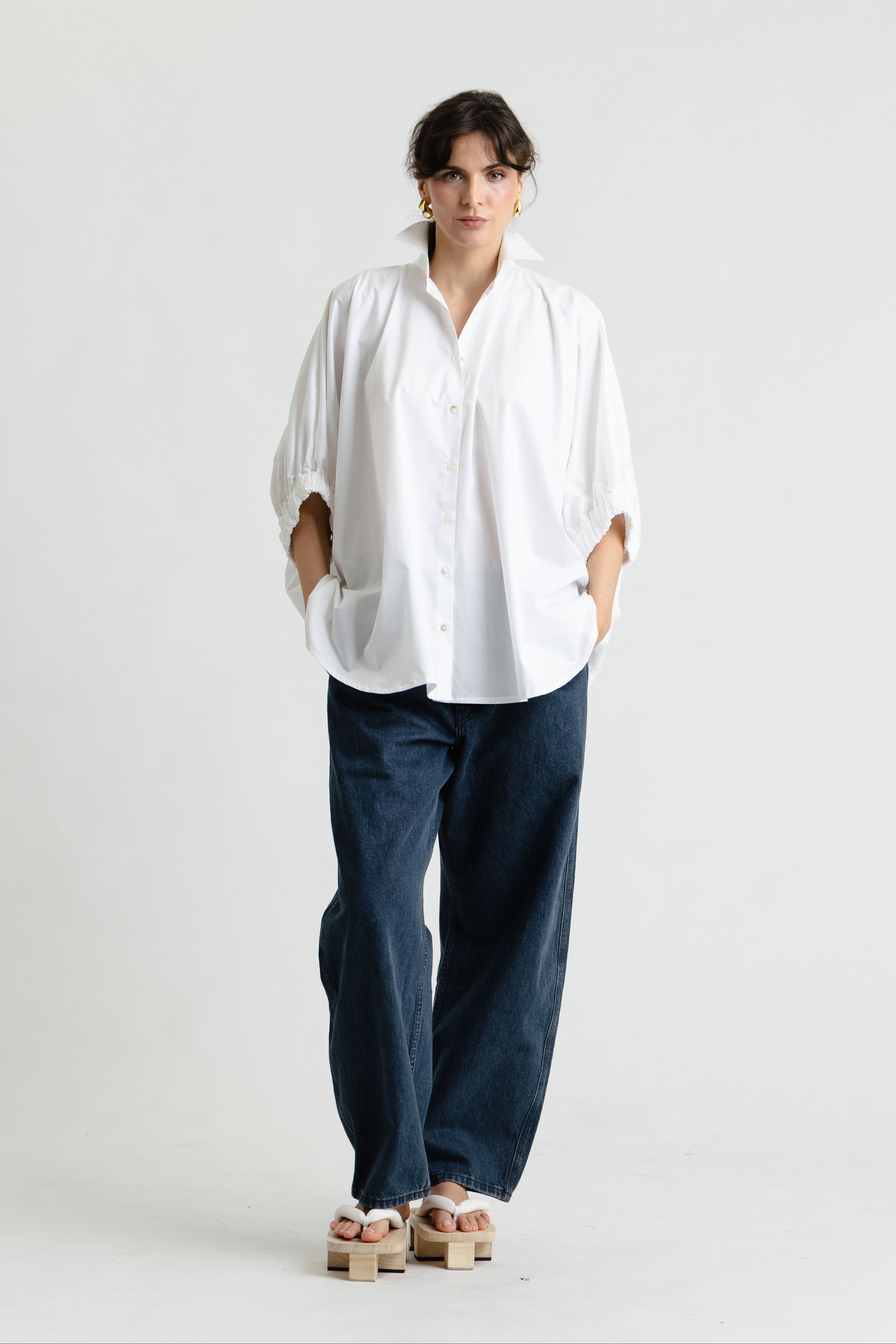 Person wearing a white shirt and blue pants on a white background