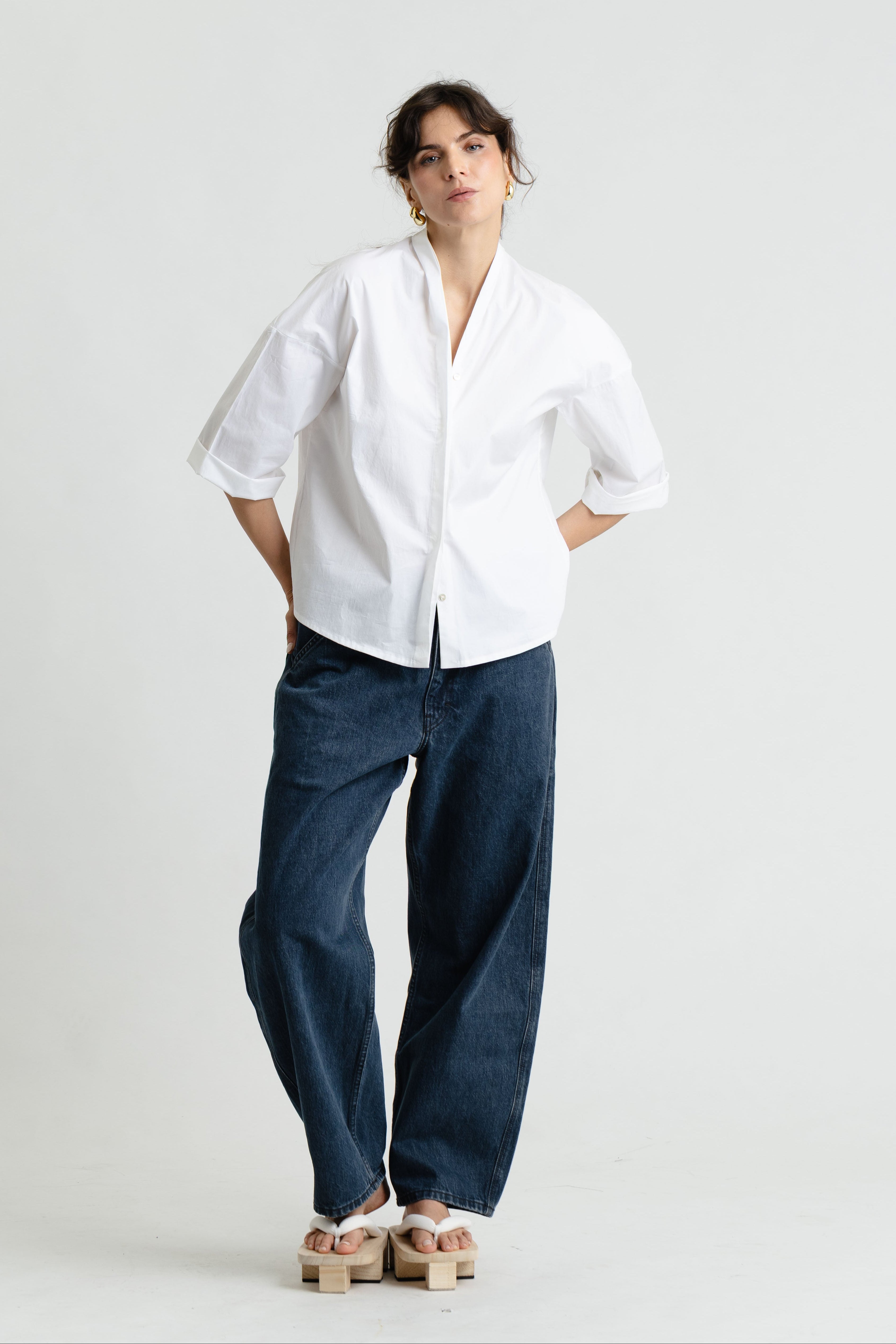 Person wearing a white shirt and blue jeans on a plain background
