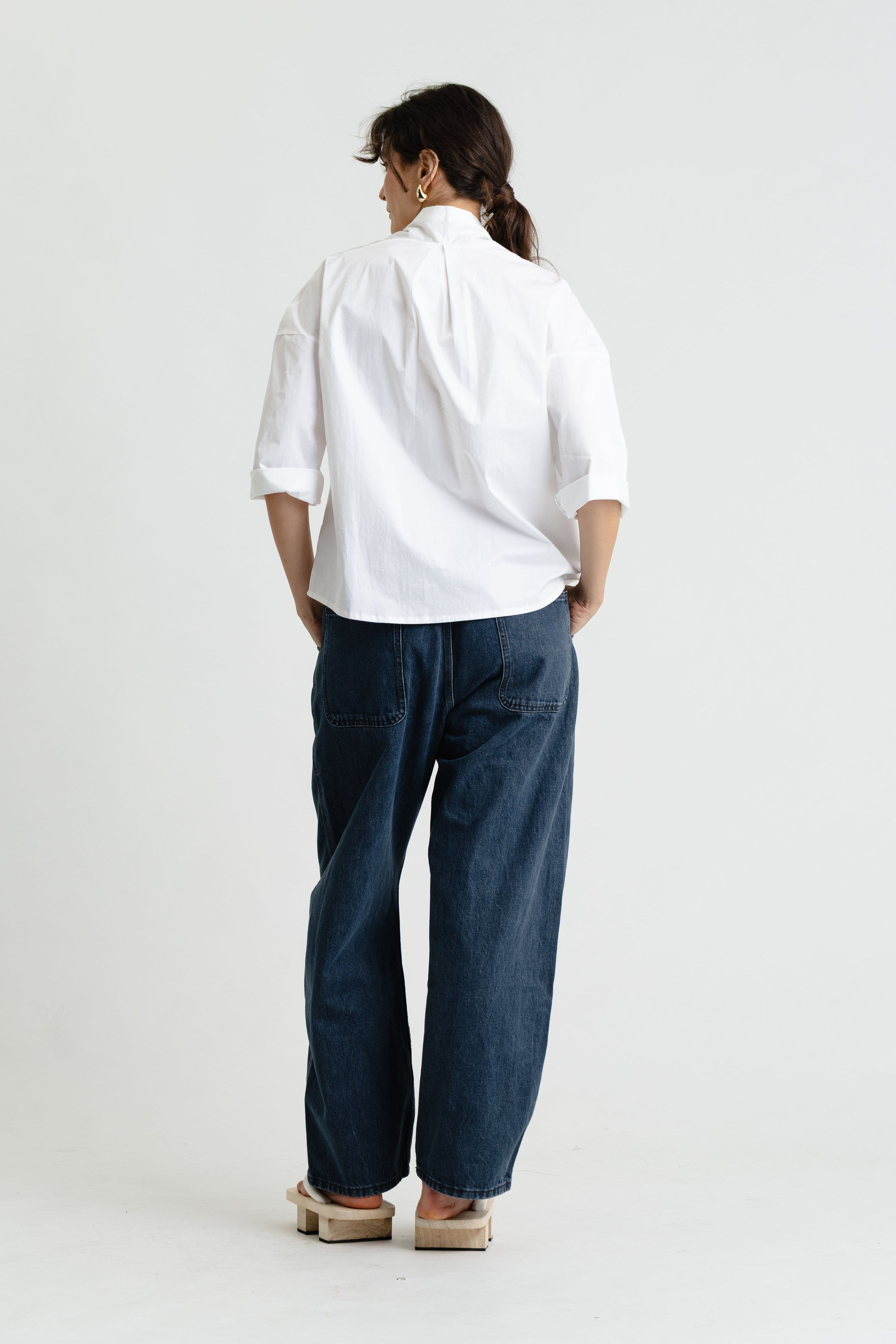 Person wearing a white shirt and blue pants on a white background