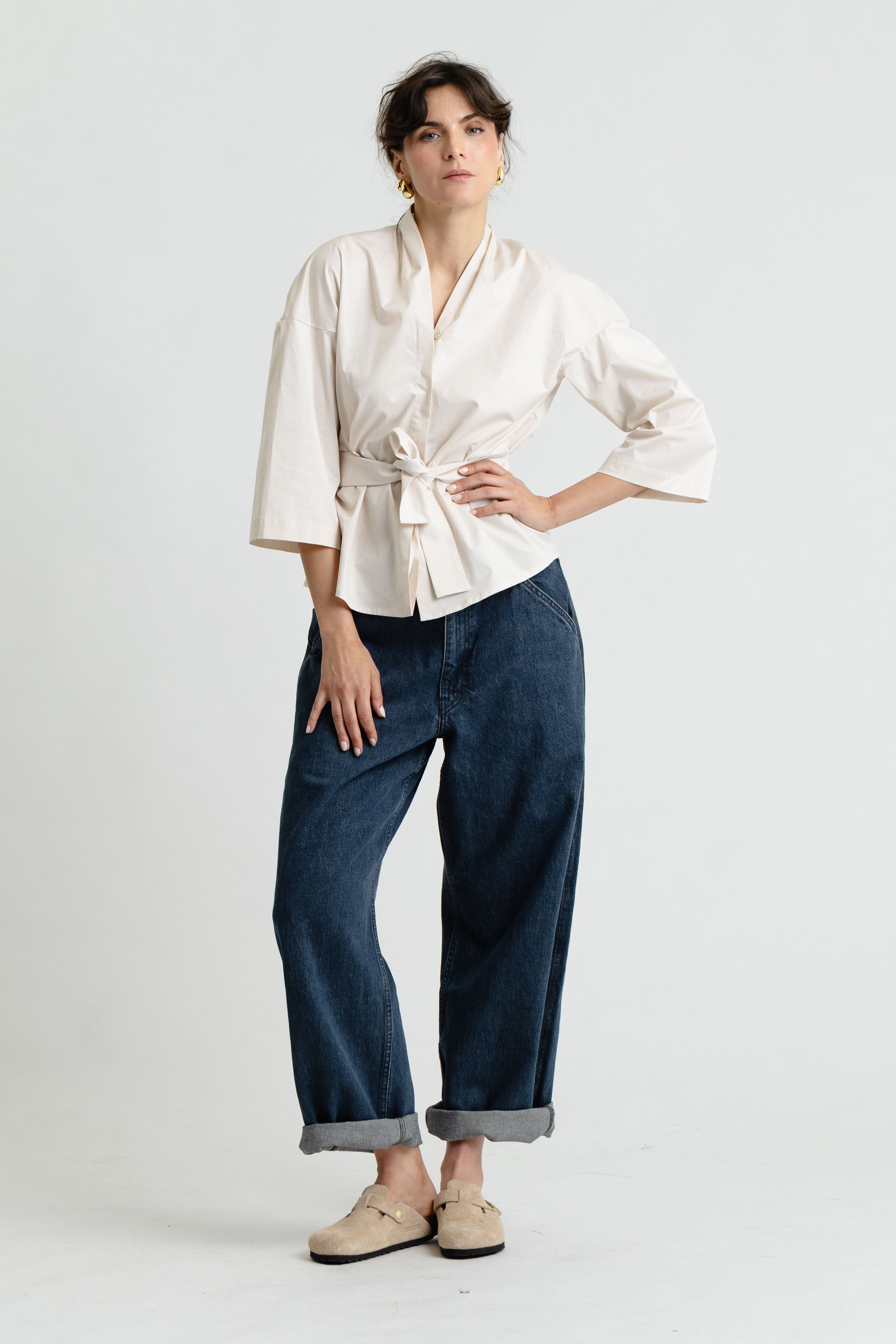 Woman wearing a white blouse and blue pants on a white background