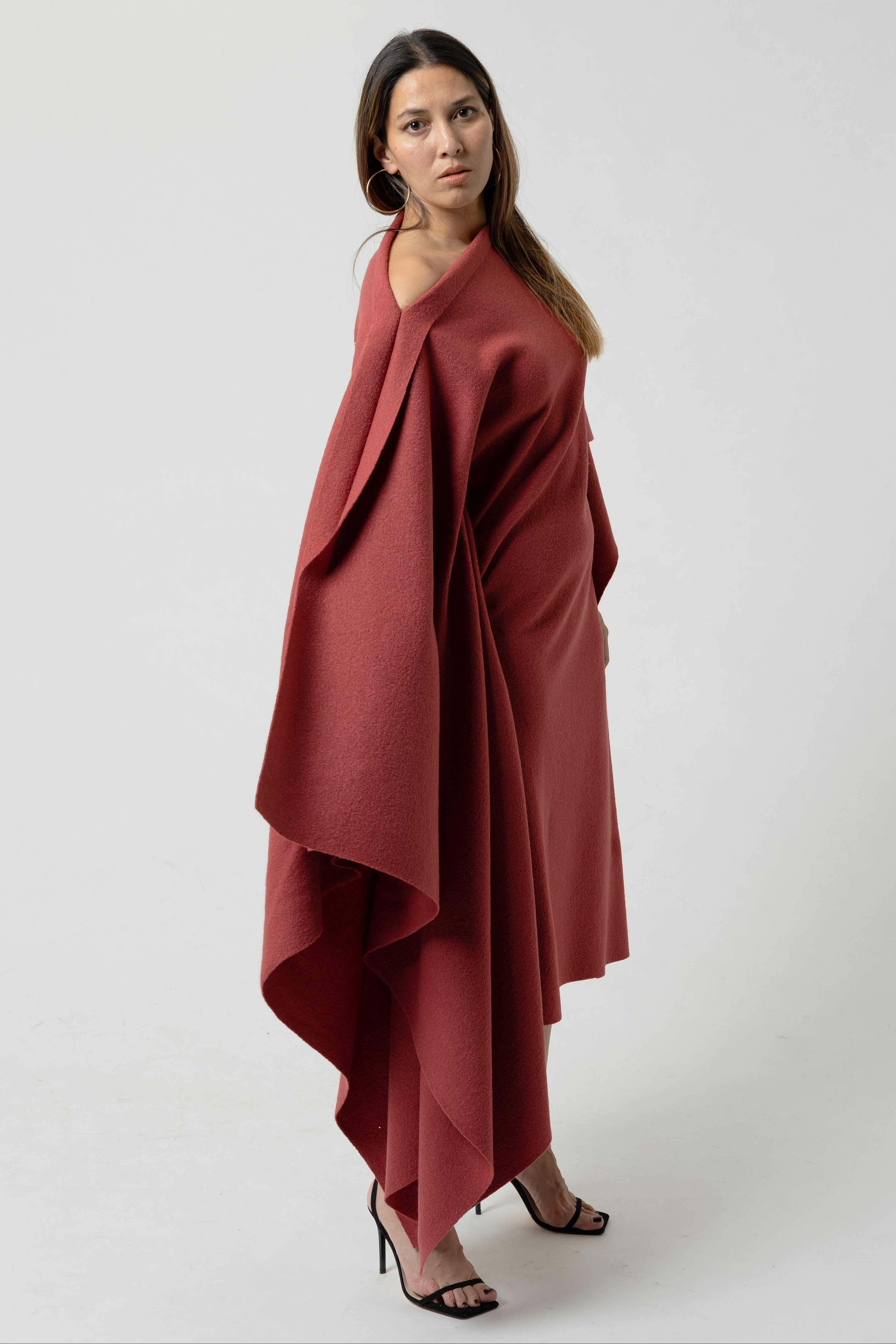 Woman wearing a red draped garment on a white background