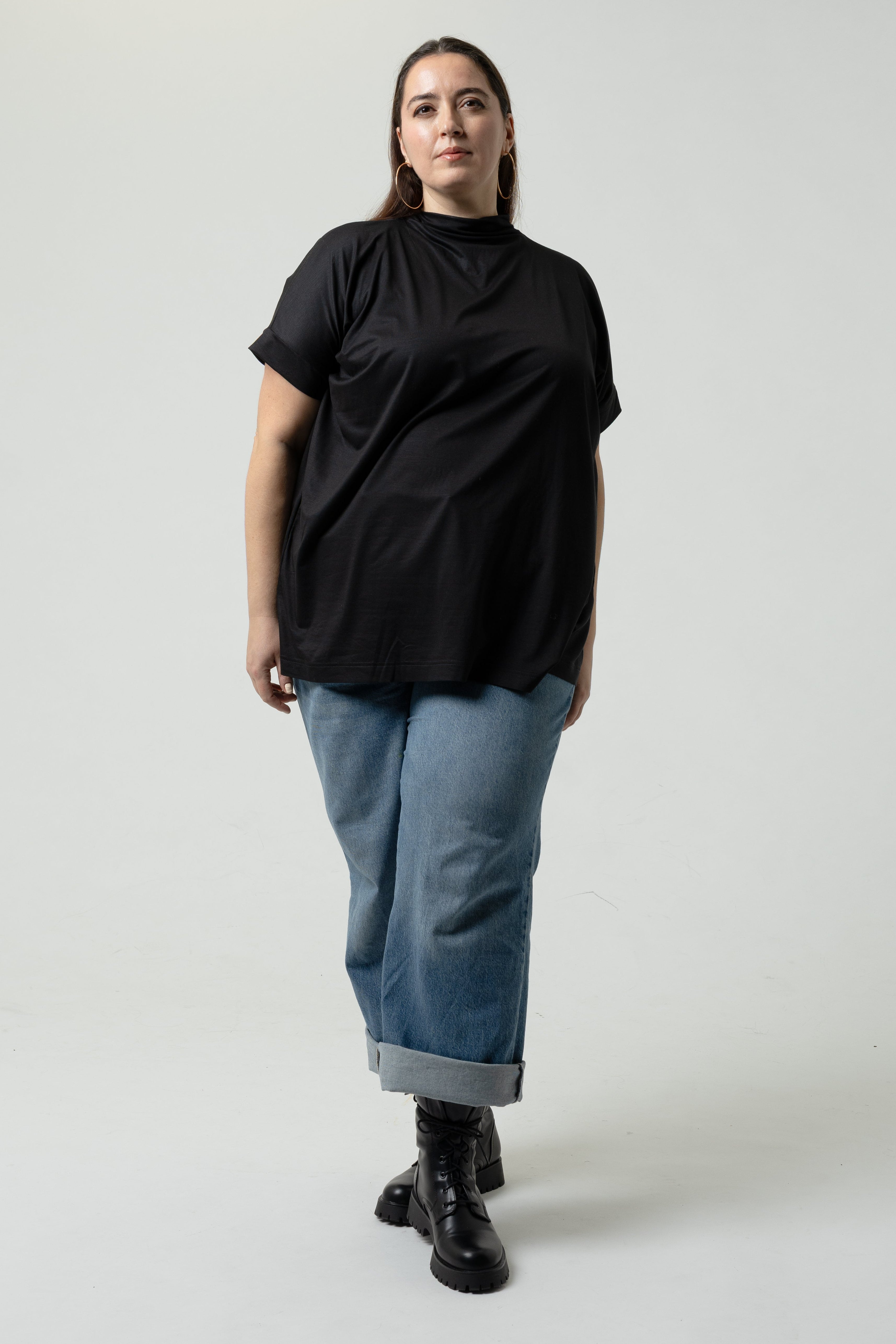 Person wearing a black top and blue jeans on a white background