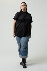 Person wearing a black top and blue jeans on a white background