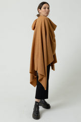 Person wearing a brown cape over a plain background