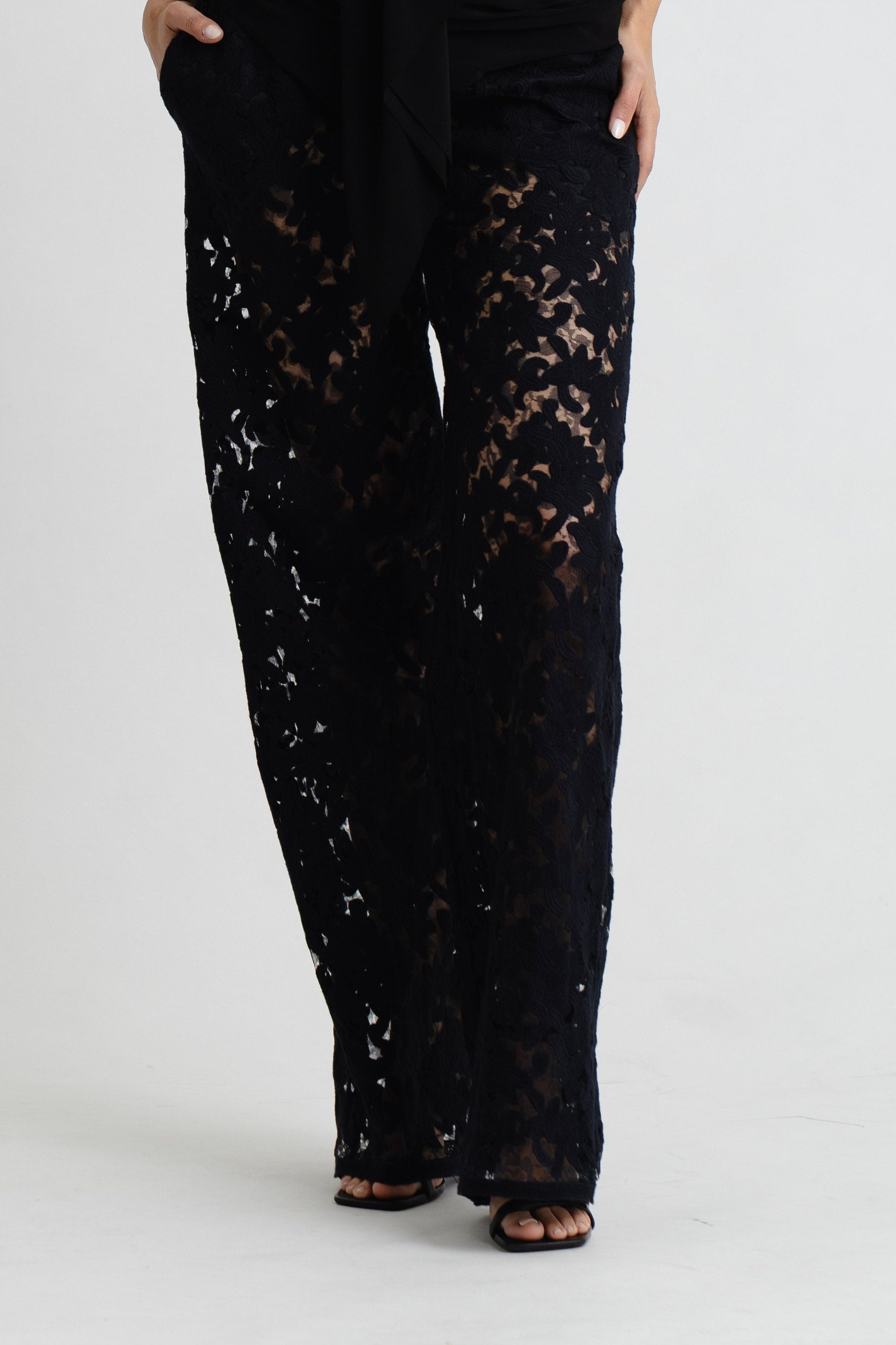 Woman wearing a black lace jumpsuit on a white background