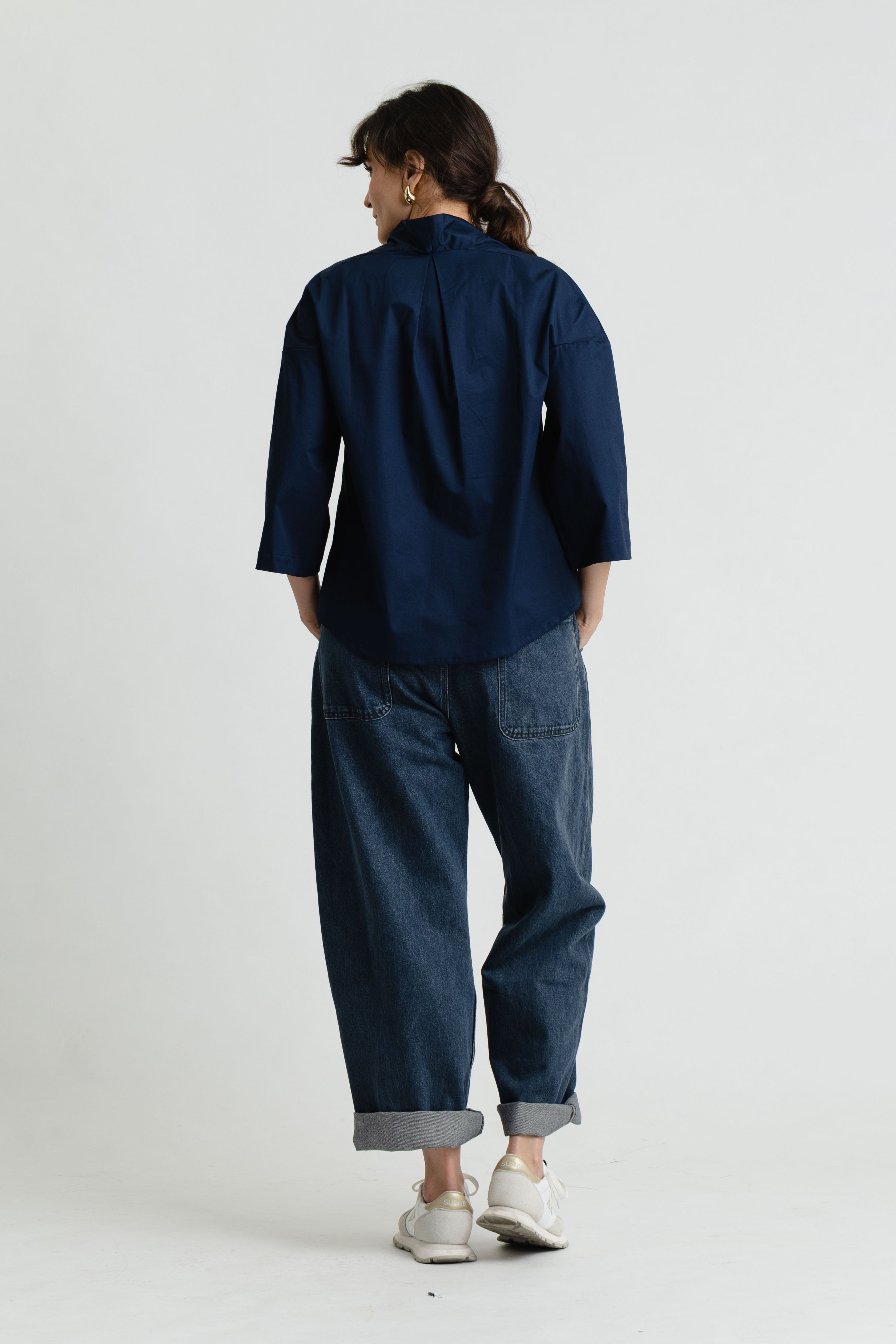 Person wearing a navy blue shirt and jeans on a white background
