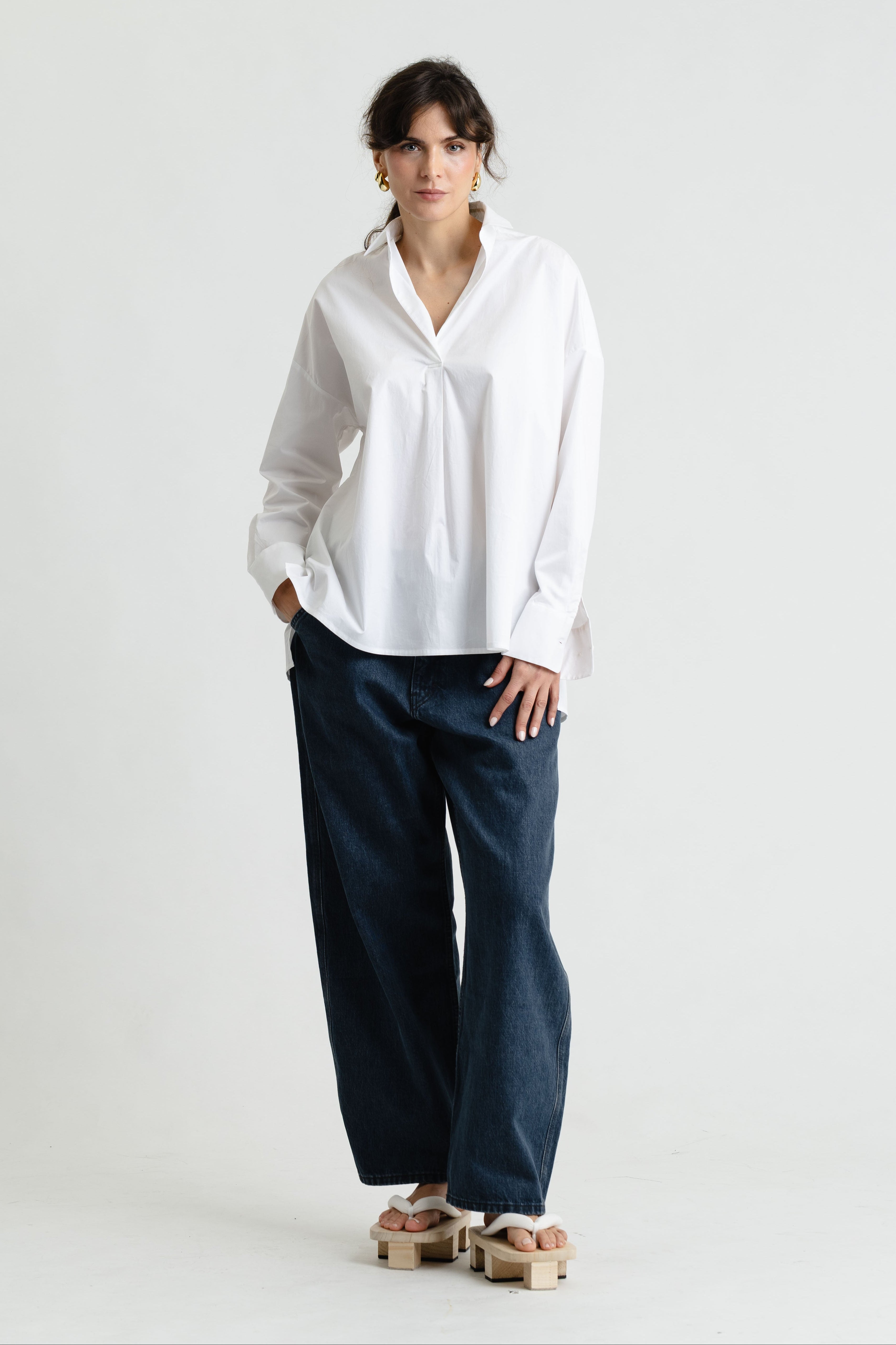 Person wearing a white shirt and dark pants on a white background